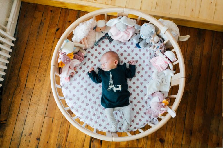 bébé qui dort dans un lit rond en bois